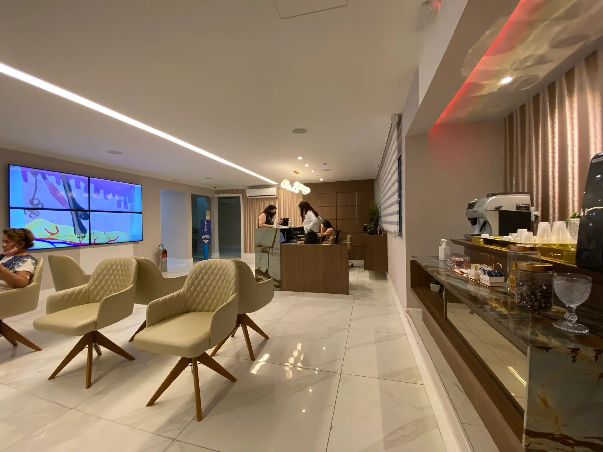 Recepção principal da Clínica Esthetica com balcão curvo e forro acústico com iluminação indireta